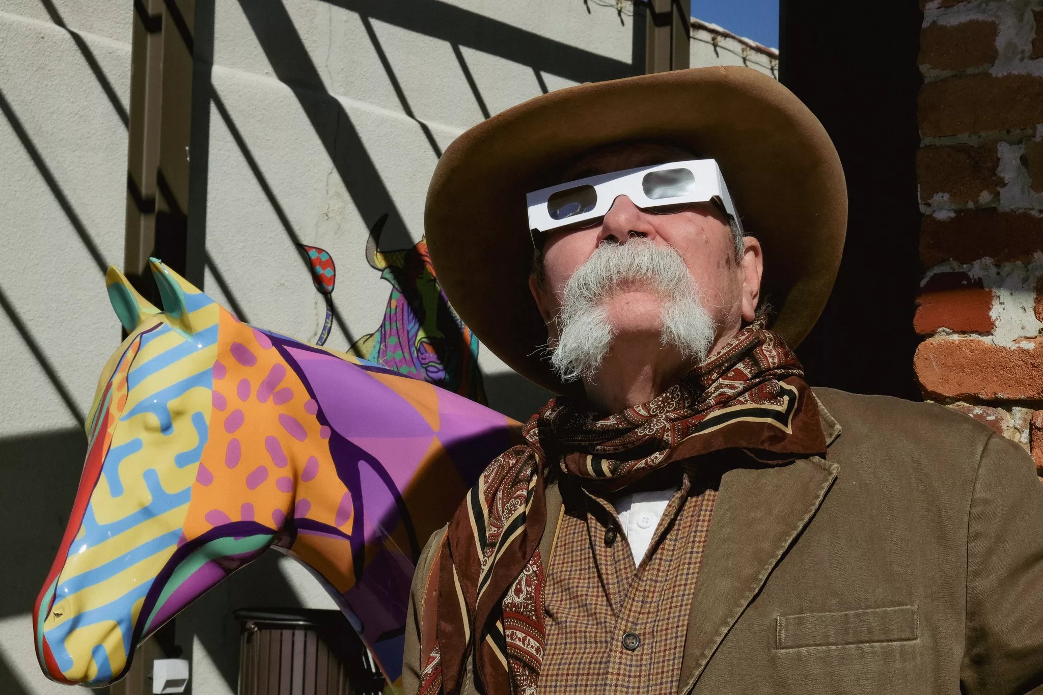 A cowboy stares at the sky wearing eclipse glasses.