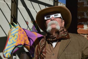 A cowboy stares at the sky wearing eclipse glasses.